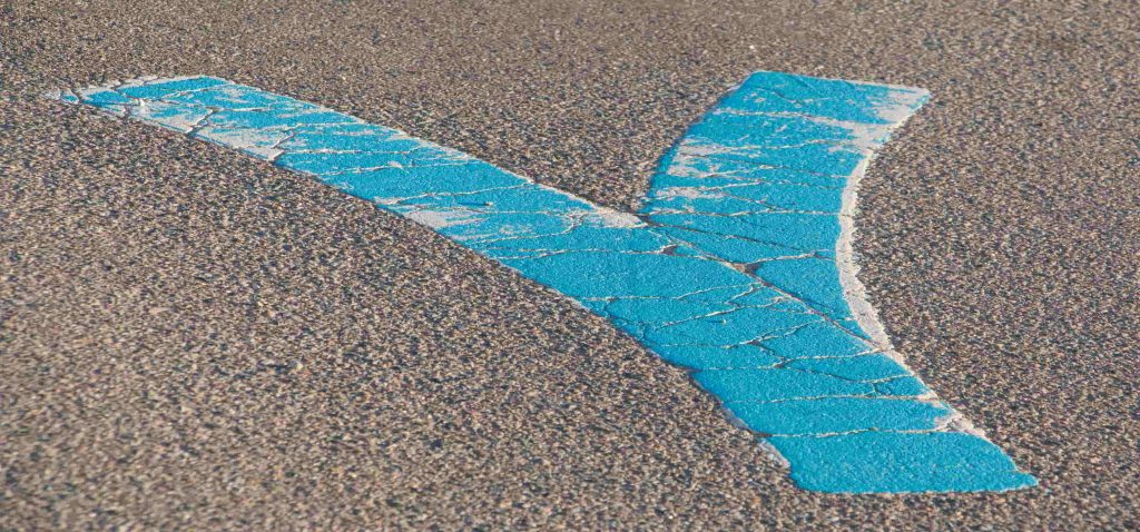 Grande letra Y azul pintada numa rua de asfalto, simbolizando a bifurcação e as diferentes possibilidades de crescimento numa carreira em Y.