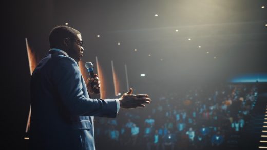 Palestrante confiante no palco de um grande auditório dominando a arte de falar em público.