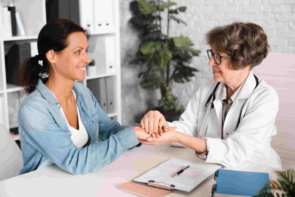 Médica segurando as mãos de uma paciente de forma acolhedora durante uma consulta, representando o apoio profissional e o cuidado com a saúde mental