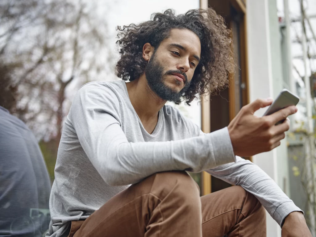 homem-pensativo-olhando-para-o-celular