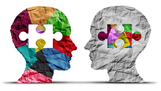 Silhuetas de duas cabeças com textura de papel em que uma peça de quebra-cabeça colorida se encaixa, simbolizando a empatia, a conexão e o sentimento de pertencimento